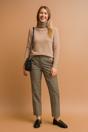 Taupe beige soft knit turtleneck sweater with ribbed cuffs and hem, styled with tailored plaid trousers, black loafers, and a quilted black shoulder bag.