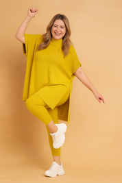 Two-piece ribbed knit coord set featuring a loose-fit oversized tunic with side slits and matching fitted ankle-length leggings, styled with chunky white sneakers for a cozy casual look.