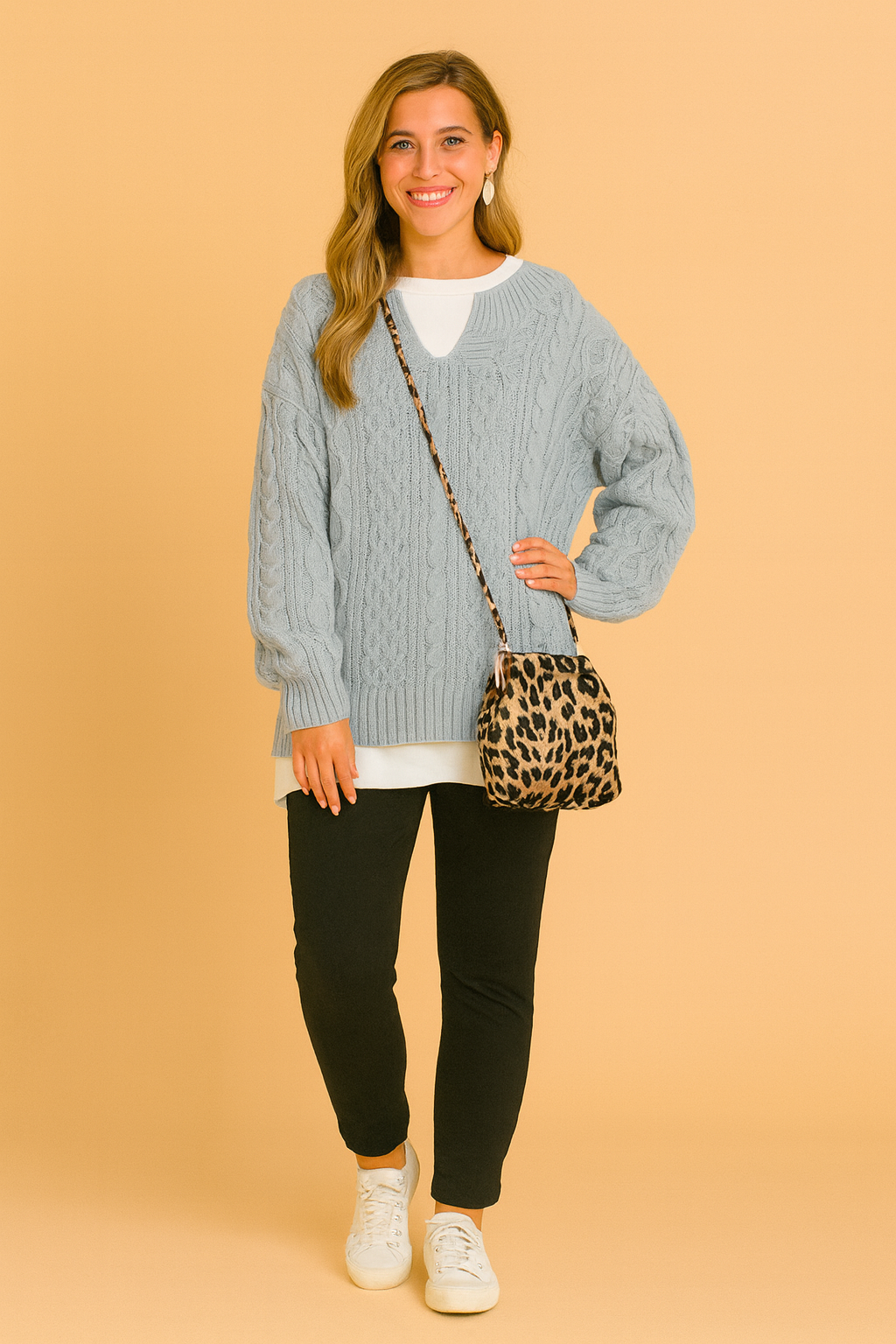Oversized sweater with classic cable pattern, paired with a white inner shirt, slim black pants, white sneakers, and a leopard-print shoulder bag