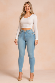 Stylish high-waist light blue skinny jeans paired with a fitted white long-sleeve crop top, designed for a flattering, modern casual look