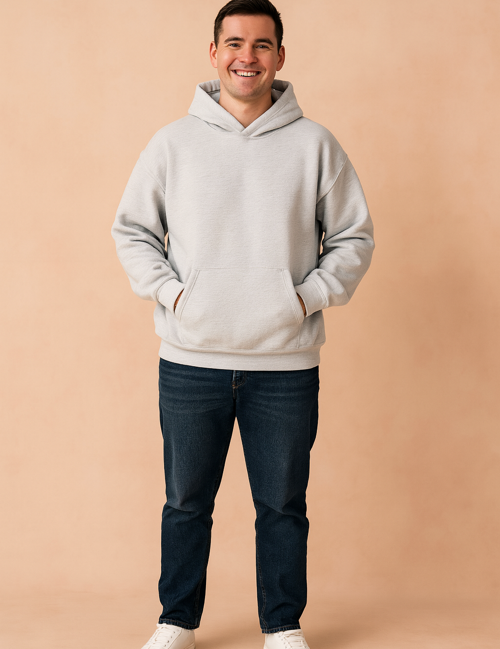 Light gray oversized hoodie with kangaroo pocket and ribbed cuffs, styled with dark blue jeans and white sneakers for a relaxed casual look.