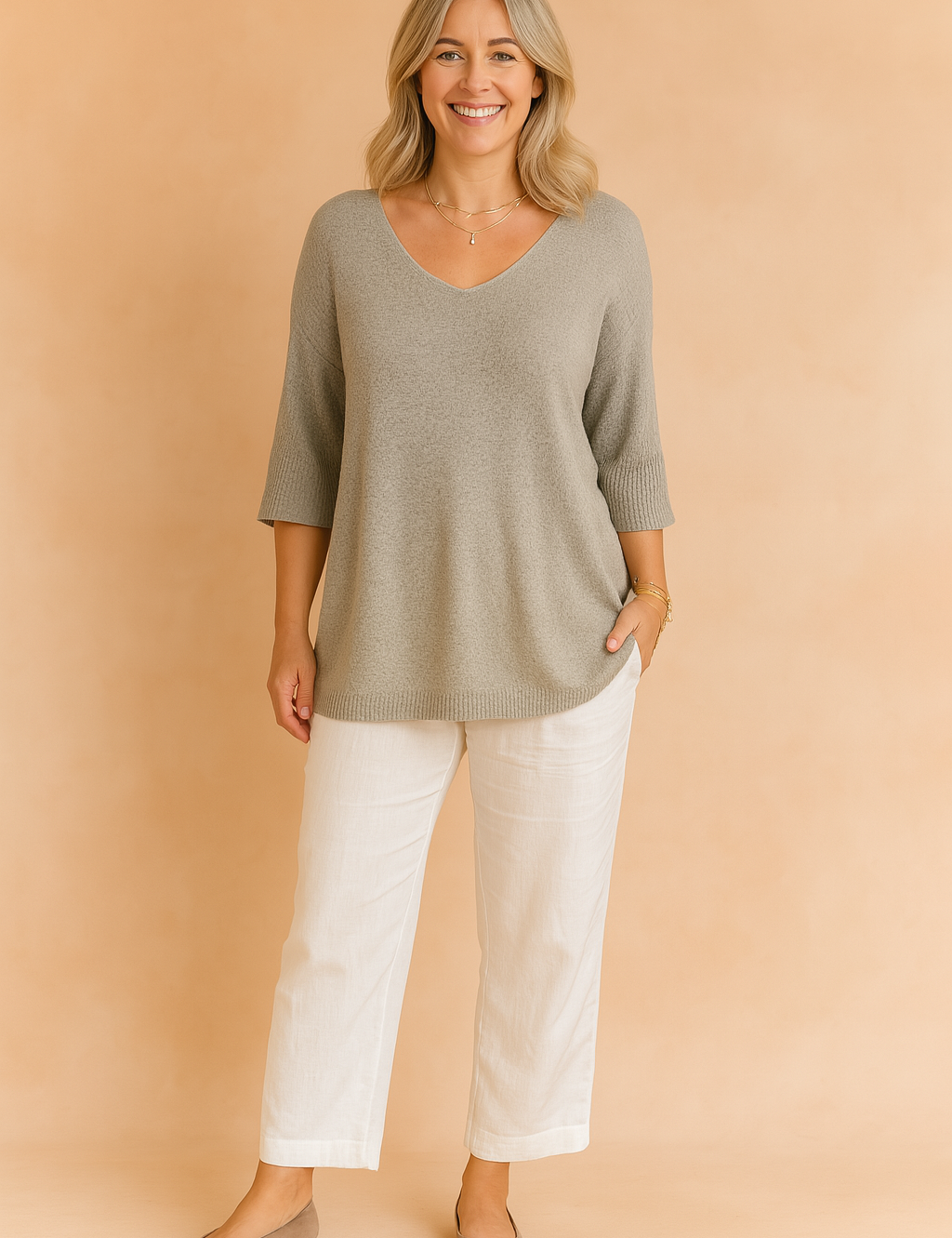 Light grey V-neck knit tunic with three-quarter sleeves, paired with white straight-leg linen trousers and taupe flats.