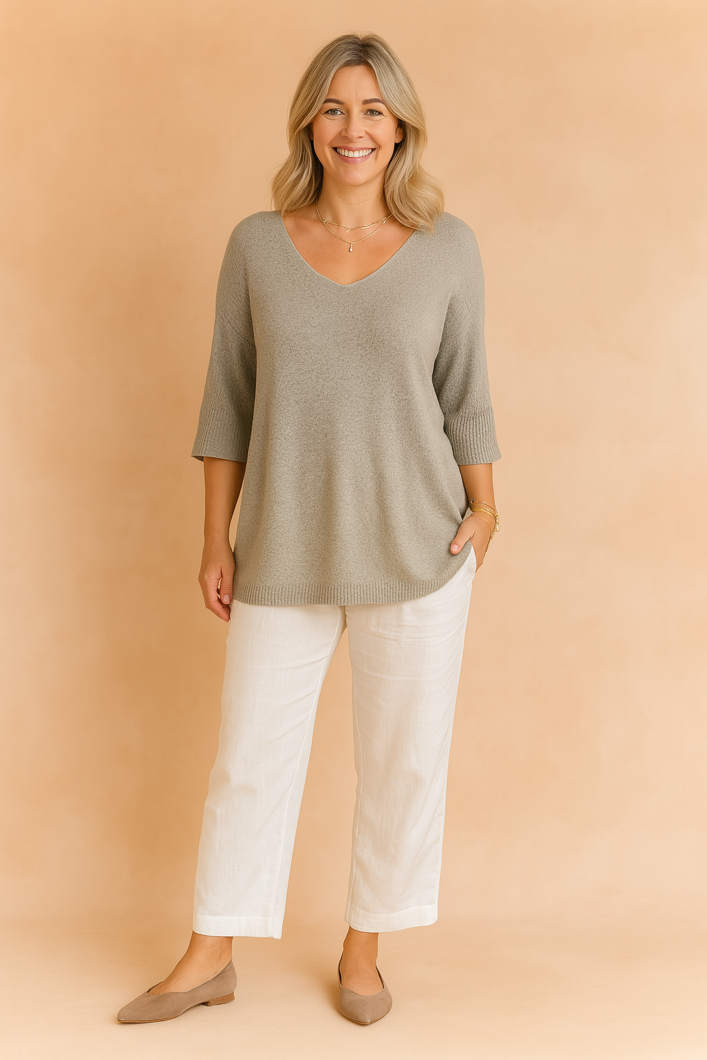 Light grey V-neck knit tunic with three-quarter sleeves, paired with white straight-leg linen trousers and taupe flats.