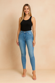 Light blue high-waist skinny jeggings with faded wash and back pockets, styled with a strapless black top and clear stiletto heels, shown from a side-back angle.