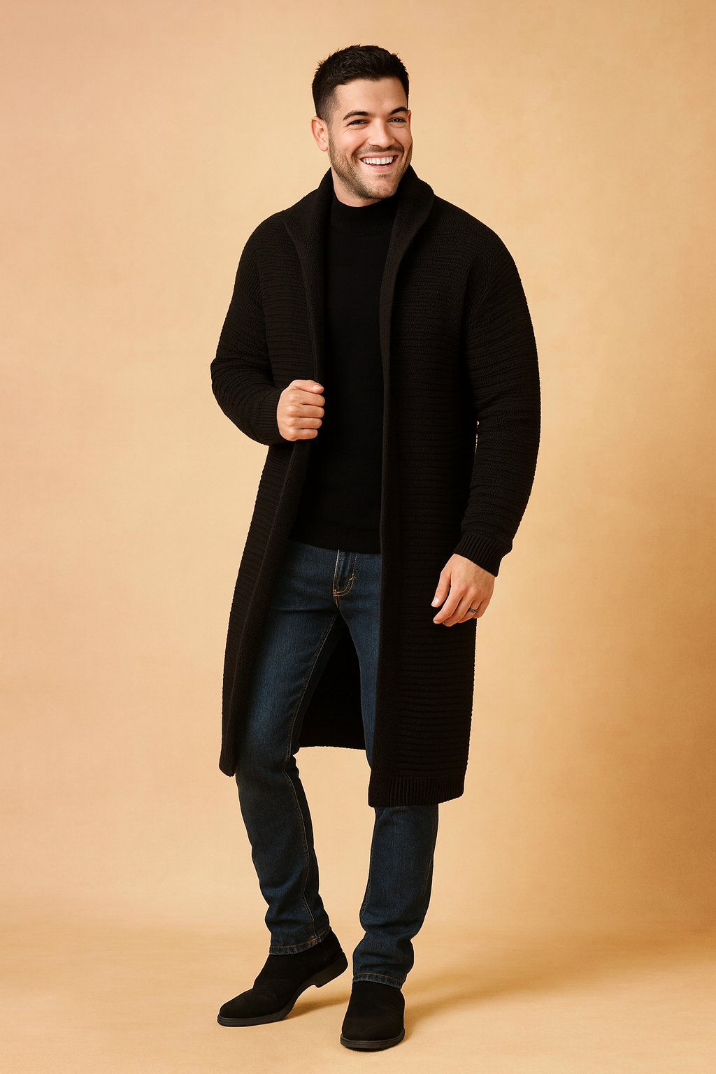 Long black ribbed knit cardigan for men, styled with a fitted black sweater, slim blue jeans, and black suede Chelsea boots.