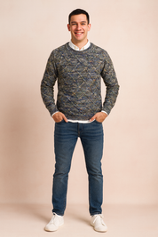 Multicolor diamond-pattern knit sweater in blue, gray, and beige tones, styled with a white shirt underneath, slim-fit jeans, and white sneakers for a smart-casual look.