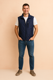 Men's navy blue outdoor vest with zippered pockets, paired with a white short-sleeve shirt, blue jeans, and taupe sneakers. The vest is designed with a sleek finish, lightweight fabric, and a straight cut for a casual yet stylish look