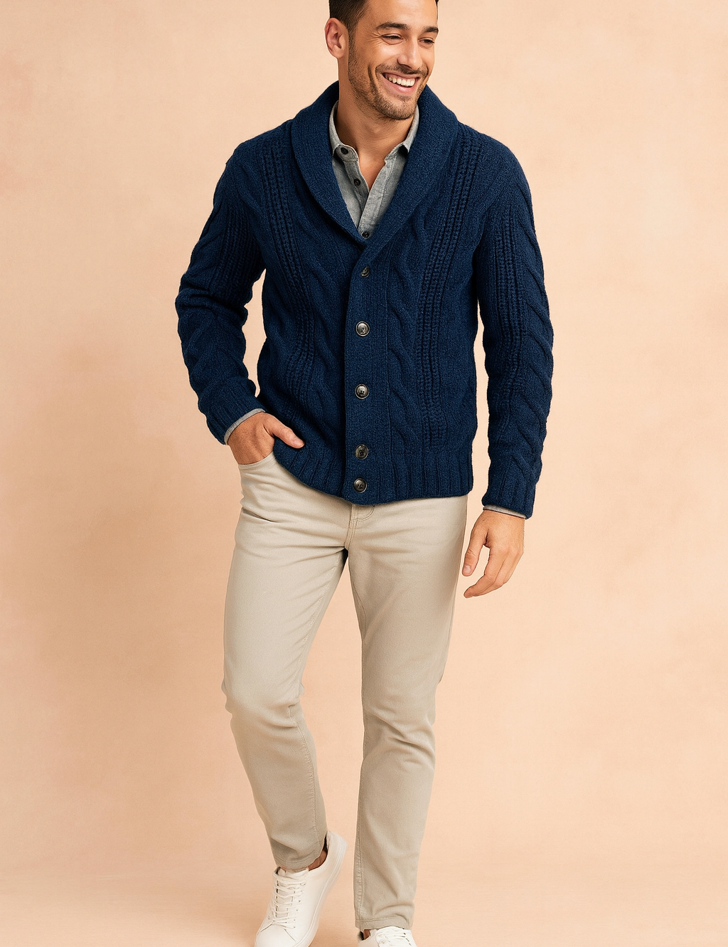Navy blue cable knit cardigan with shawl collar and button front closure, styled over a light gray shirt with beige chinos and white sneakers.