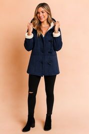 Navy blue toggle coat with white faux fur trim, styled over black distressed skinny jeans and black suede ankle boots.