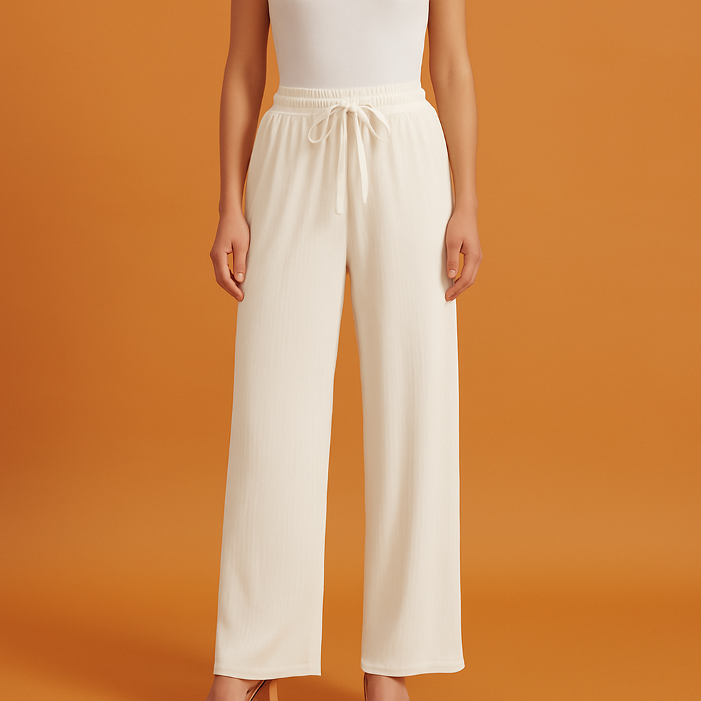 Off-white pleated wide-leg pants with a ribbed texture and drawstring waistband, styled with a white tank top and nude heels.