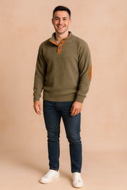 Men’s olive green ribbed pullover sweater with buttoned placket and brown suede elbow patches, styled with dark blue jeans and white sneakers.