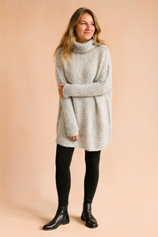 Light grey oversized chunky knit turtleneck sweater with drop shoulders, paired with black fitted leggings and leather ankle boots for a cozy autumn outfit.
