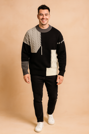 Men’s patchwork knit sweater with black, grey, and white color blocks featuring cable-knit and quilted textures, designed with visible stitch details for a bold, modern style.