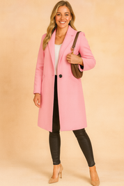 Long pastel pink single-breasted coat with structured lapels, styled with black slim pants, white top, and beige heels.
