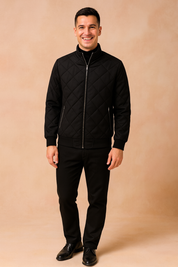Men’s quilted black bomber jacket with diamond stitching, front zipper closure, and ribbed cuffs paired with slim black pants.