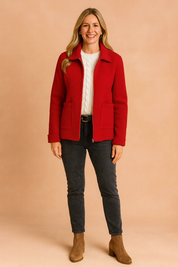 Red wool zip-up jacket with patch pockets layered over a cream cable-knit sweater, styled with washed black jeans and tan ankle boots.