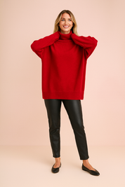 Oversized red turtleneck sweater with ribbed cuffs and hem, styled with black faux leather slim-fit pants and minimalist black flats