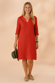 Minimalist V-neck shift dress with three-quarter sleeves and a relaxed A-line silhouette, tailored in a lightweight, textured red fabric with a clean, unembellished finish.