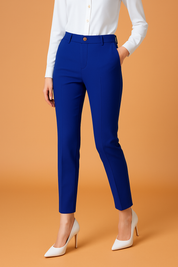 Royal blue slim-fit ankle trousers with belt loops and front button detail, styled with a tucked-in white button-up blouse and white pointed heels.