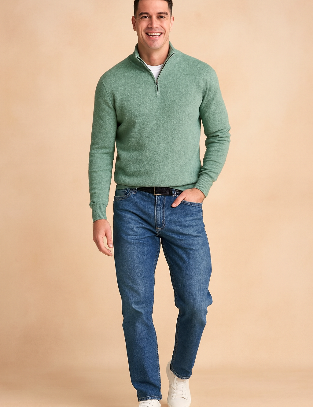 Men’s sage green quarter-zip sweater layered over a white crew-neck t-shirt, styled with blue straight-leg jeans, black leather belt, and white sneakers.