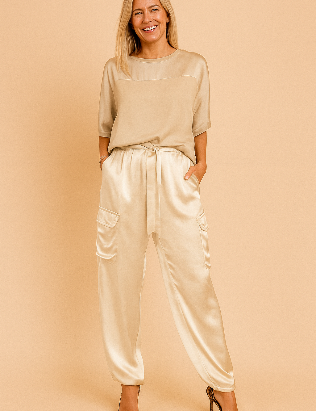 Matching satin co-ord set featuring a smooth, loose-fit blouse with half sleeves and a pair of high-rise jogger-style cargo pants with flap pockets and a drawstring tie at the waist.

