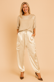 Matching satin co-ord set featuring a smooth, loose-fit blouse with half sleeves and a pair of high-rise jogger-style cargo pants with flap pockets and a drawstring tie at the waist.

