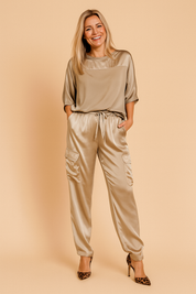 Two-piece satin co-ord set featuring a relaxed-fit blouse with a smooth matte upper panel and short sleeves, paired with high-waisted cargo jogger pants that have functional flap pockets and a drawstring waistband.
