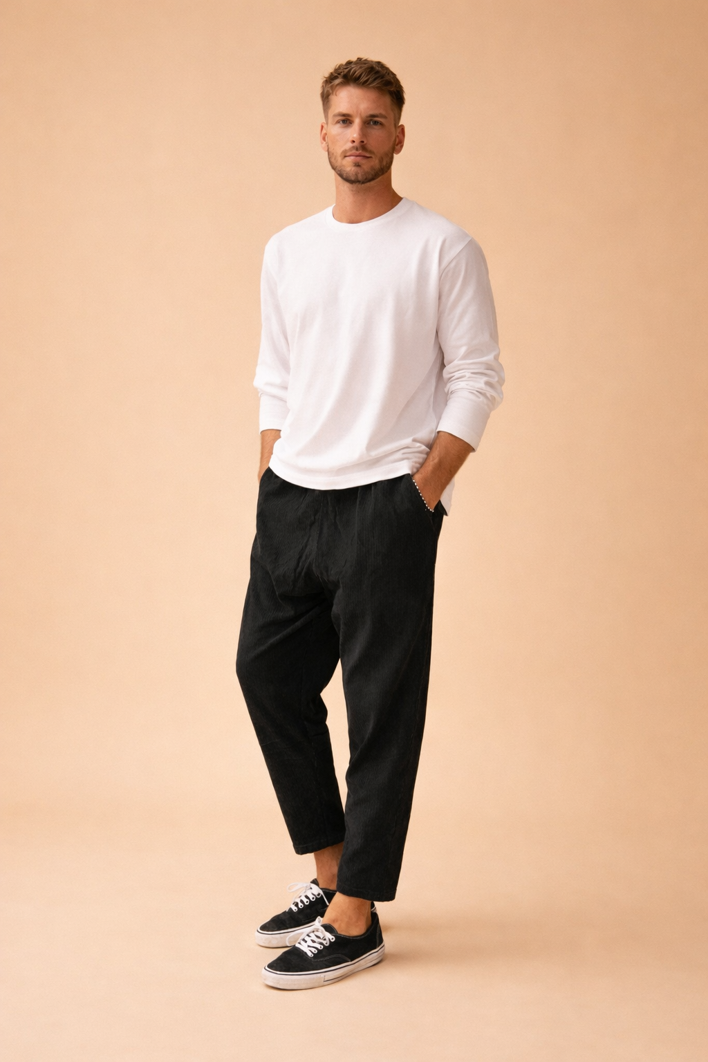 Black tapered ankle-length trousers with a clean straight finish, styled with a minimalist long-sleeve top and low-profile lace-up sneakers for a modern casual outfit.