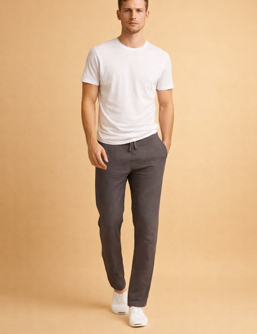 Slim-fit charcoal gray lightweight drawstring trousers with a tapered ankle-length cut, paired with a clean white short-sleeve crew-neck T-shirt and minimalist white low-top sneakers.