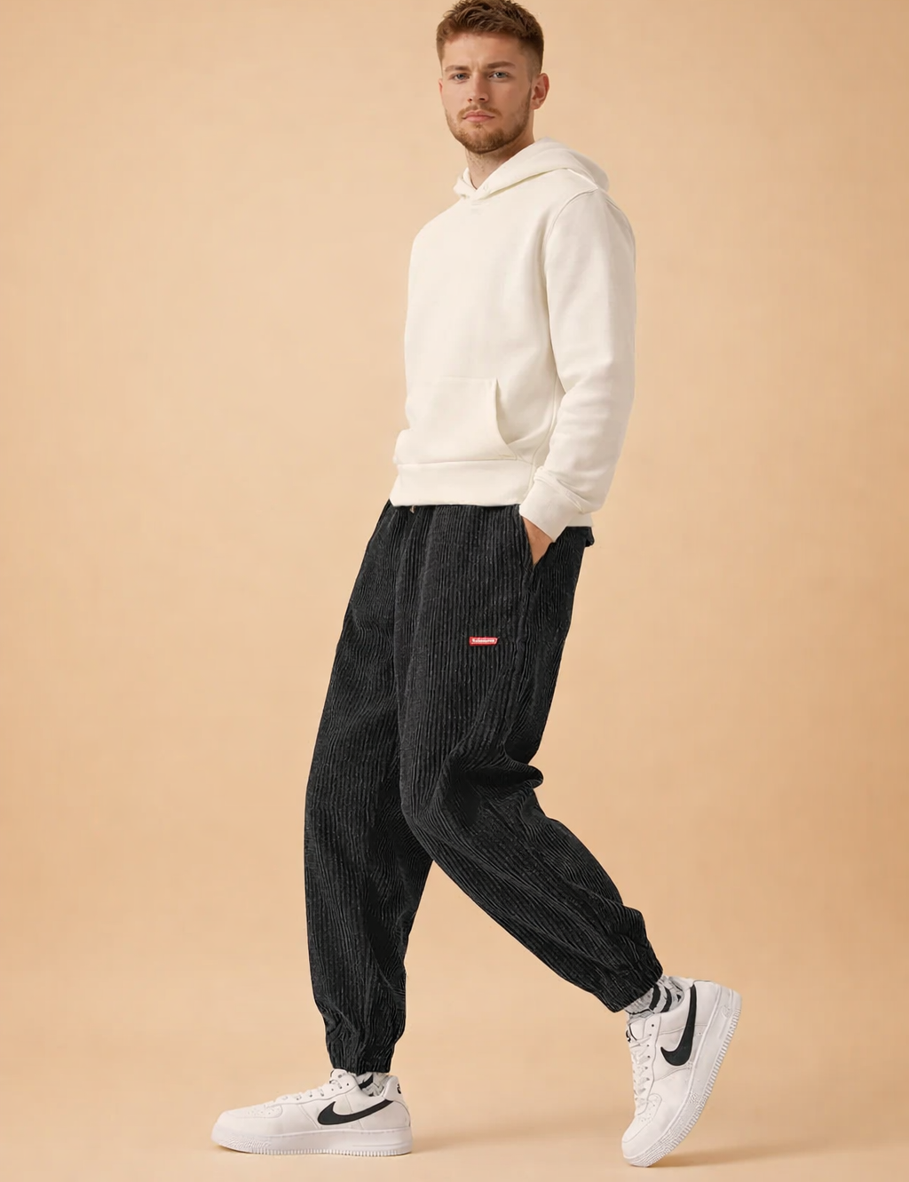 Relaxed-fit corduroy jogger pants with ribbed texture, elastic waistband and cuffs, styled with a minimalist hooded sweatshirt and clean low-top sneakers for a modern casual look.