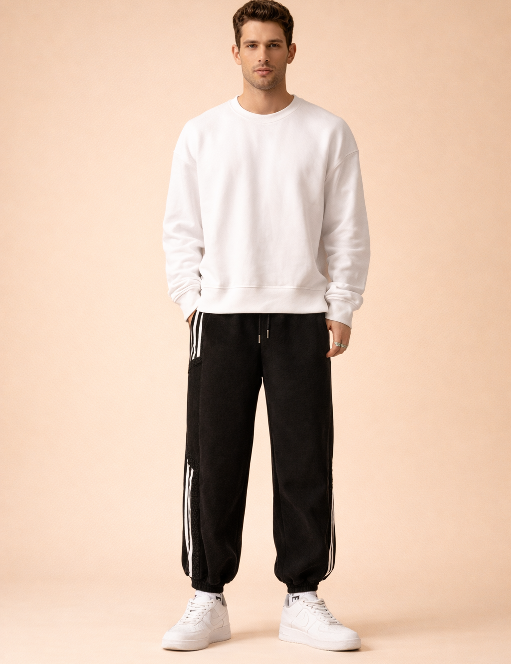 Relaxed-fit athletic jogger pants with elastic waistband and drawstring, tapered legs with elastic cuffs, clean side stripe detailing, and smooth structured drape, styled with a minimalist long-sleeve sweatshirt and classic low-profile sneakers for a modern casual look.