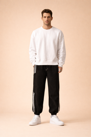 Relaxed-fit athletic jogger pants with elastic waistband and drawstring, tapered legs with elastic cuffs, clean side stripe detailing, and smooth structured drape, styled with a minimalist long-sleeve sweatshirt and classic low-profile sneakers for a modern casual look.