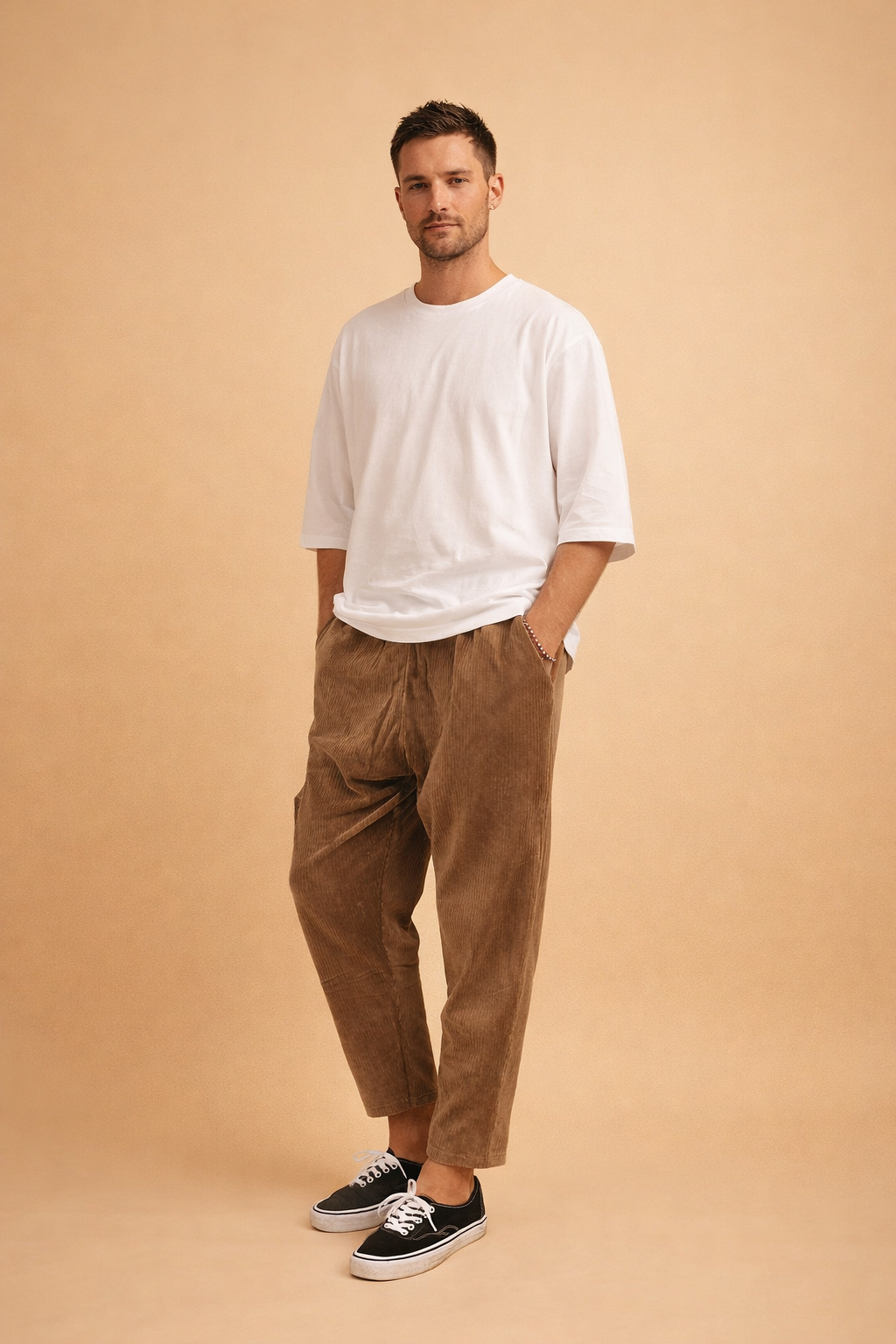 Relaxed-fit corduroy trousers with a straight-leg cut, soft vertical rib texture, mid-rise waist, and cropped ankle length, styled with a clean oversized short-sleeve top and low-profile lace-up sneakers for a modern casual look.