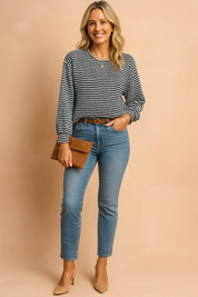 Black and white textured knit sweater with horizontal stripes, crew neckline, and relaxed fit paired with mid-rise light wash skinny jeans, accessorized with a tan suede clutch.