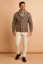 Taupe button-up cable knit cardigan with shawl collar, ribbed cuffs, and textured cable patterns, styled over a casual shirt and paired with slim off-white pants and dark brown lace-up shoes.
