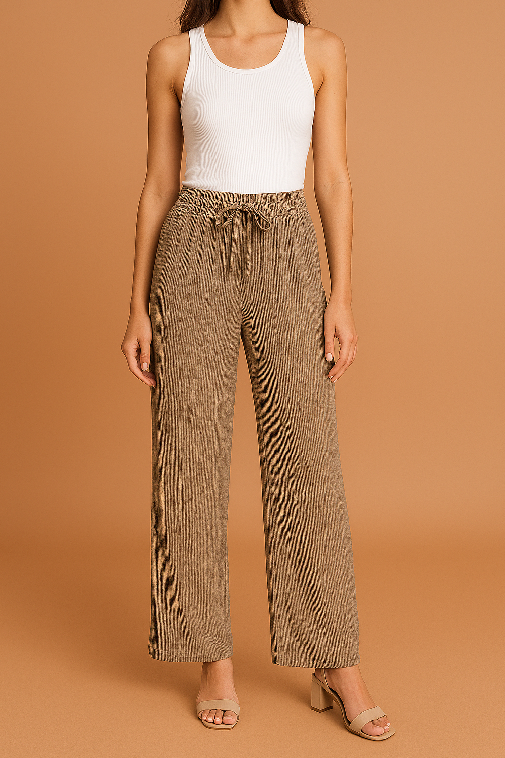 Taupe wide-leg pleated pants with a ribbed texture and adjustable drawstring waistband, styled with a fitted white tank top and nude block-heeled sandals.