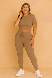 Taupe ribbed knit two-piece set featuring a short sleeve crop top and high-waisted drawstring leggings, styled with white sneakers.