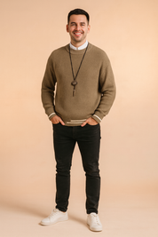 Men’s taupe ribbed knit sweater with white stripe cuff and hem accents, paired with black slim-fit trousers and a necklace for a stylish, casual look.