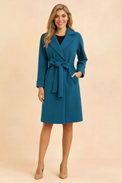 Teal belted wrap coat with wide lapels and front pockets, styled with a black inner top and beige pumps.