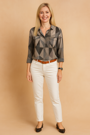 Women's button-up shirt with long sleeves and a pointed collar, featuring a geometric triangle pattern in shades of black, grey, and taupe, paired with white fitted pants and a brown belt.