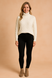 Ivory turtleneck sweater with textured basketweave knit, neatly tucked into high-waisted black skinny pants and styled with taupe ankle boots.