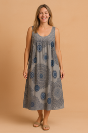 Sleeveless bohemian sundress with a loose A-line silhouette, featuring intricate circular mandala prints in dark navy and soft blue on a light gray base, finished with a scoop neckline and subtle pleating for added flow.