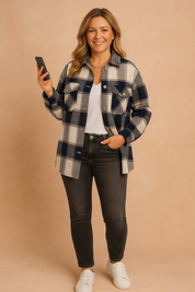 Navy and cream oversized plaid shirt jacket with flap pockets and silver snap buttons, styled over a white V-neck tee and fitted washed black jeans, paired with white leather sneakers and a silver chain necklace.