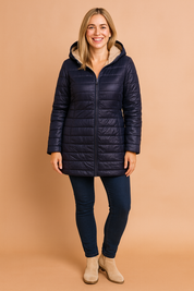Navy blue quilted hooded winter coat with plush beige fleece lining, front zip closure, and hip-length cut, styled with a lightweight insulated finish and subtle shine ideal for cold-weather layering.