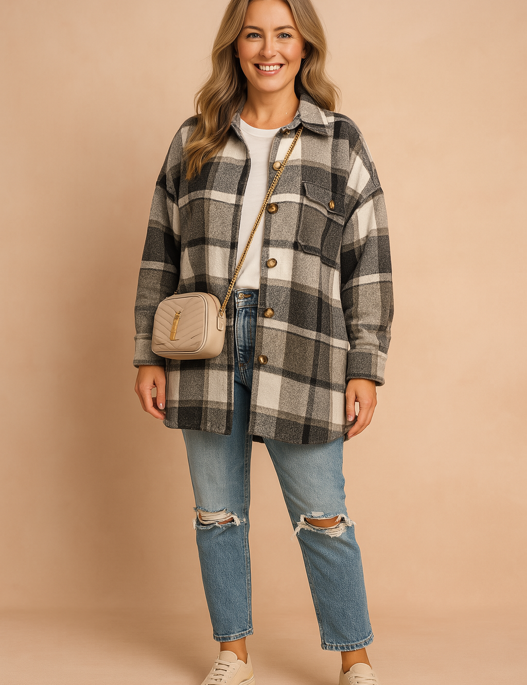 Oversized plaid shacket in black, grey, and white tones with large tortoiseshell buttons, paired with distressed blue denim jeans and a white crew-neck tee, styled with a beige quilted crossbody bag and cream low-top sneakers.