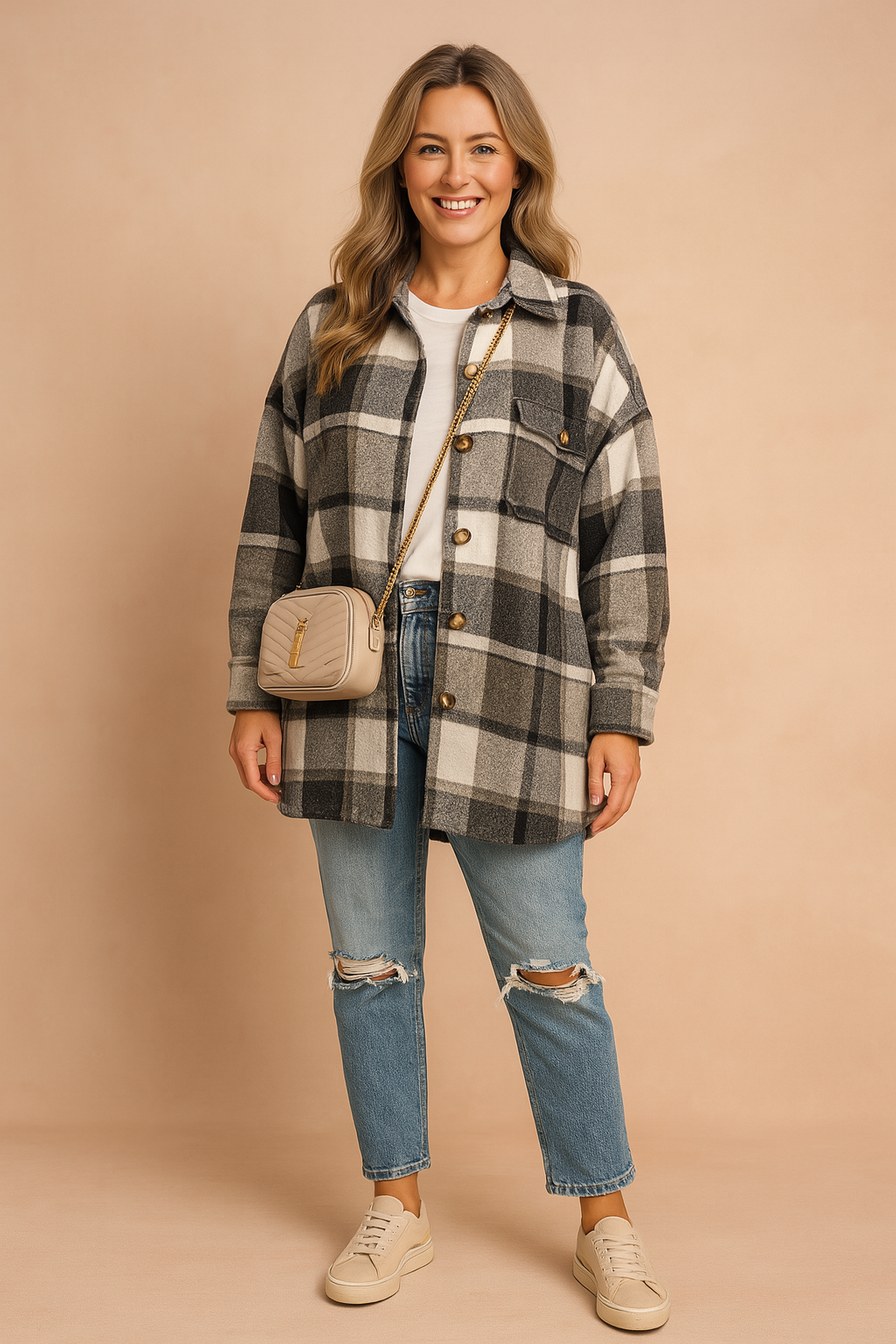 Oversized plaid shacket in black, grey, and white tones with large tortoiseshell buttons, paired with distressed blue denim jeans and a white crew-neck tee, styled with a beige quilted crossbody bag and cream low-top sneakers.