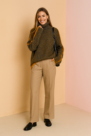 Chunky rib-knit multicolor turtleneck sweater with orange side stripes paired with tailored beige wide-leg trousers and black leather loafers.