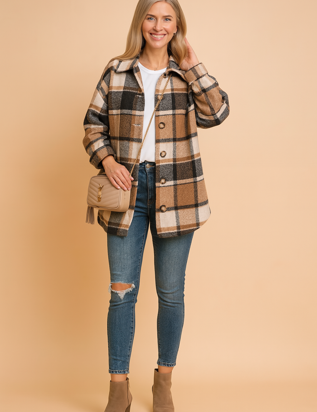 Women's oversized plaid shacket in tan, white, and black tones, styled over a classic white crew-neck tee and paired with ripped skinny blue jeans and taupe ankle boots, complemented by a beige quilted crossbody bag.