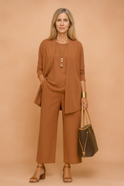 Elegant terracotta three-piece women's outfit featuring a longline open-front blazer, relaxed-fit sleeveless top, and wide-leg trousers, all crafted from a smooth, matte-finish fabric in a solid earth-tone hue.