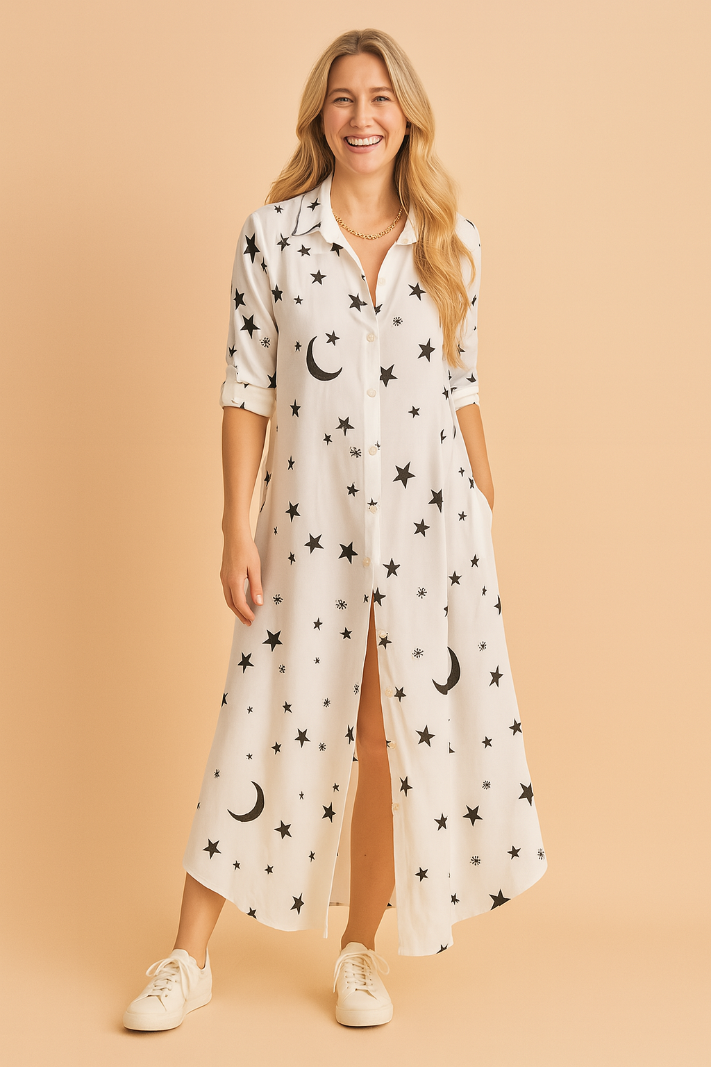 White full-length button-down dress featuring black celestial prints of stars, moons, and snowflake-like symbols, designed with rolled sleeves and a relaxed silhouette.